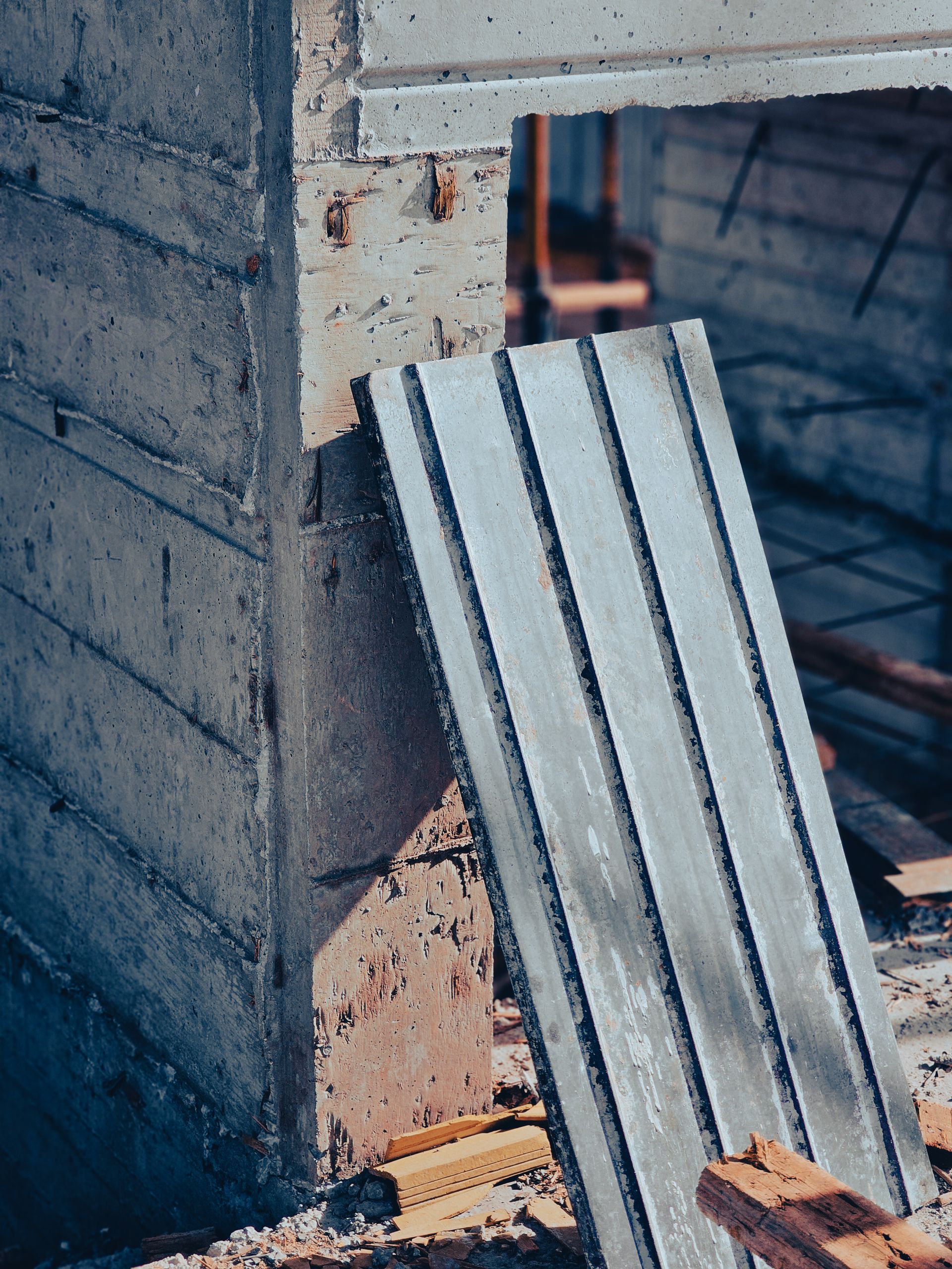 Reste der Wandschalung lehnen an einer fertigen Betonwand auf der Baustelle